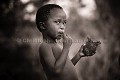 Enfant Bushman en train de manger de la viande grillée de Lièvre sauteur (Pedetes capensis). Désert du Kalahari Central. Botswana. - Botswana 
 Bushmen 
 people 
 Kalahari 
 Central 
 Desert,
child,
enfant,
manger,
eating,
food,
nourriture,
viande,
 
