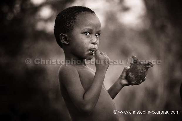 Enfant Bushman en train de manger de la viande